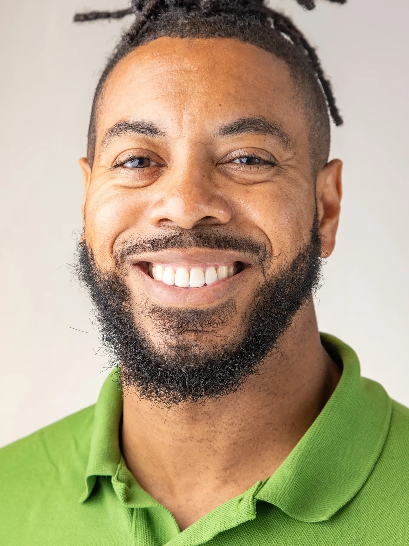 William smiling in a green polo for a commercial portrait